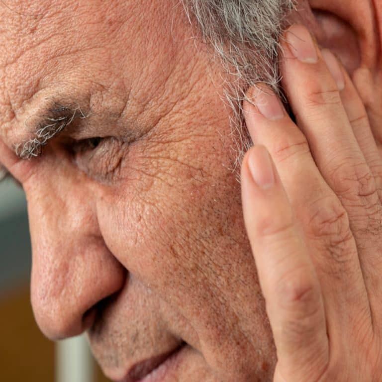 a close up image of an older man touching his ear